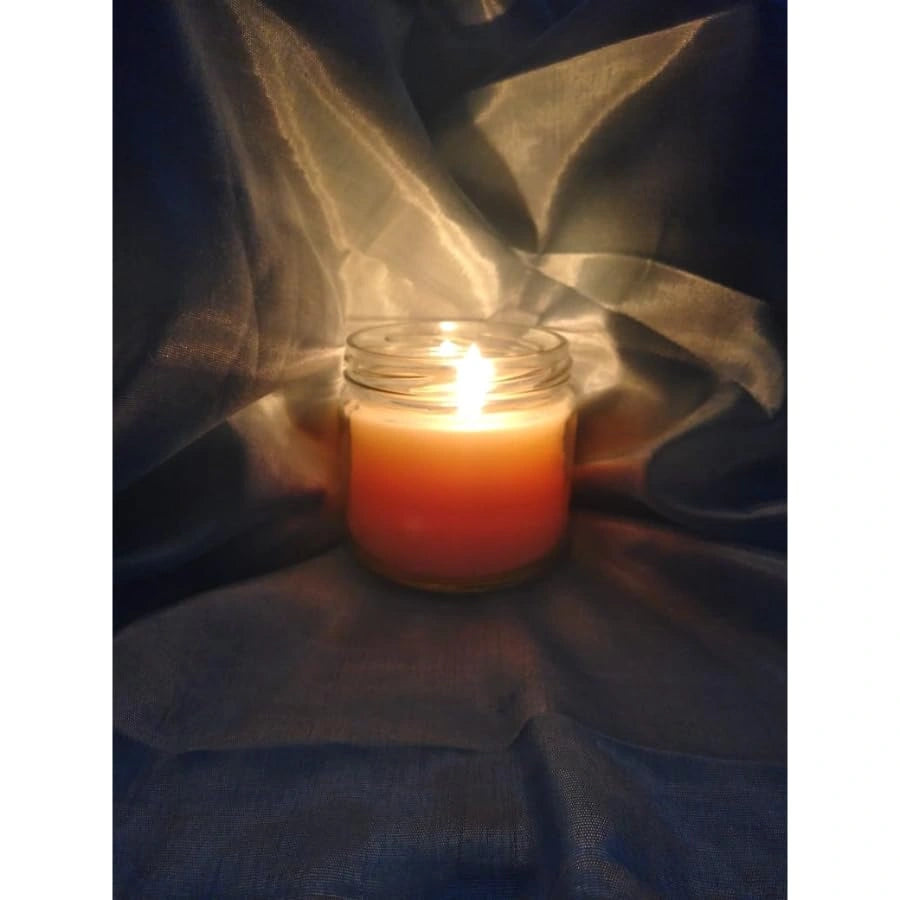 Glass jar candle burning with warm glow creating relaxing and cozy atmosphere indoors