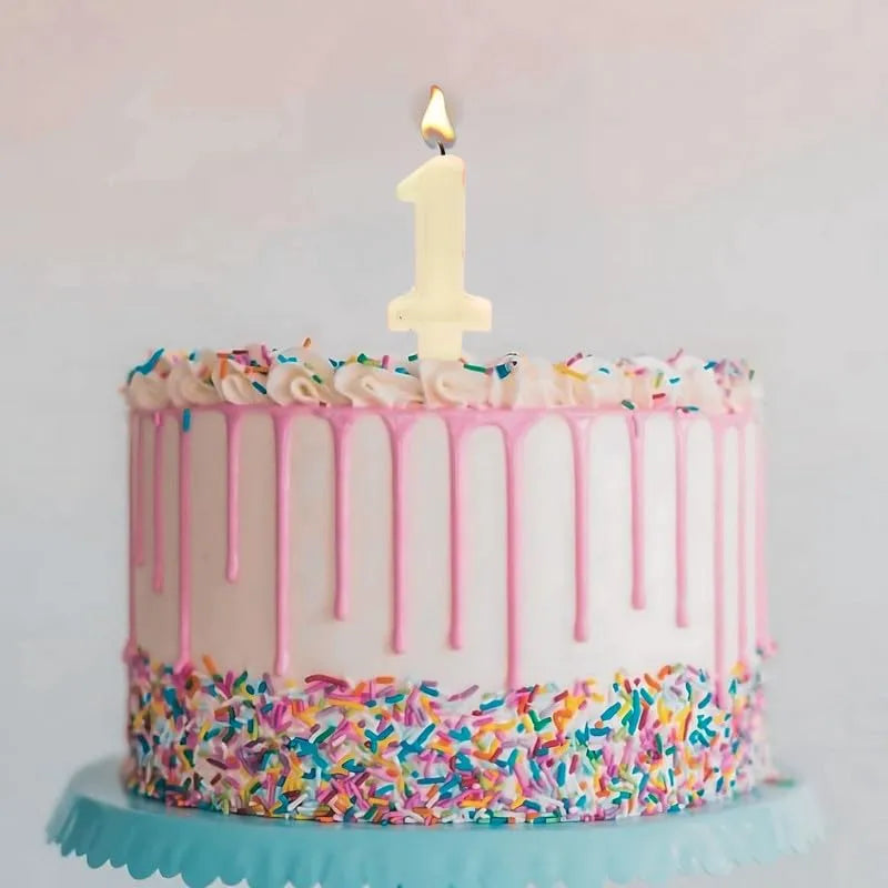 White number 1 candle placed on a decorated birthday cake