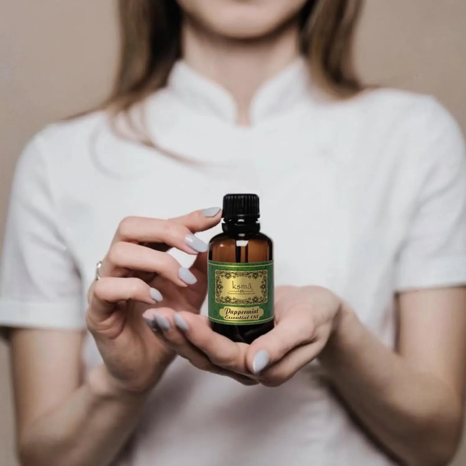 Person holding peppermint essential oil bottle in hand