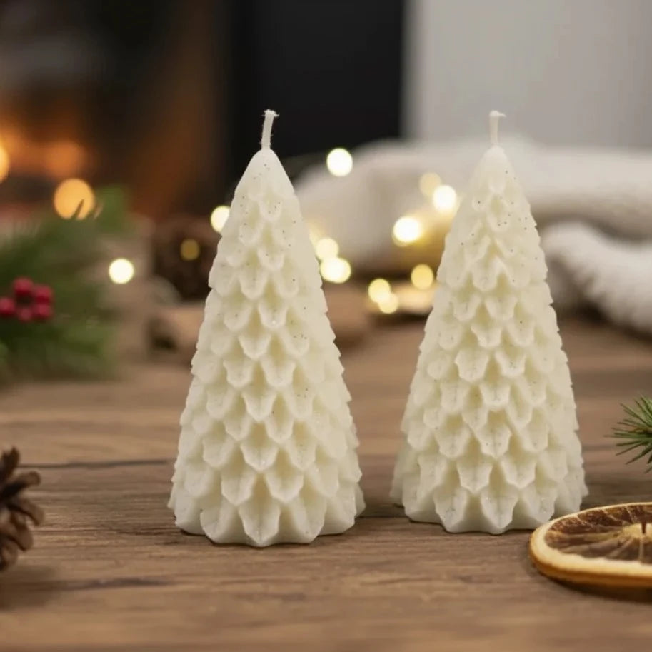 Set of two tree shaped candles placed together on wooden surface with warm festive background
